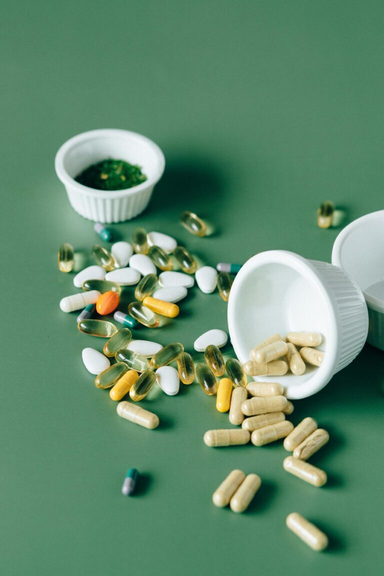 Variety of supplements and pills scattered on a green background, showcasing modern medicine concepts.